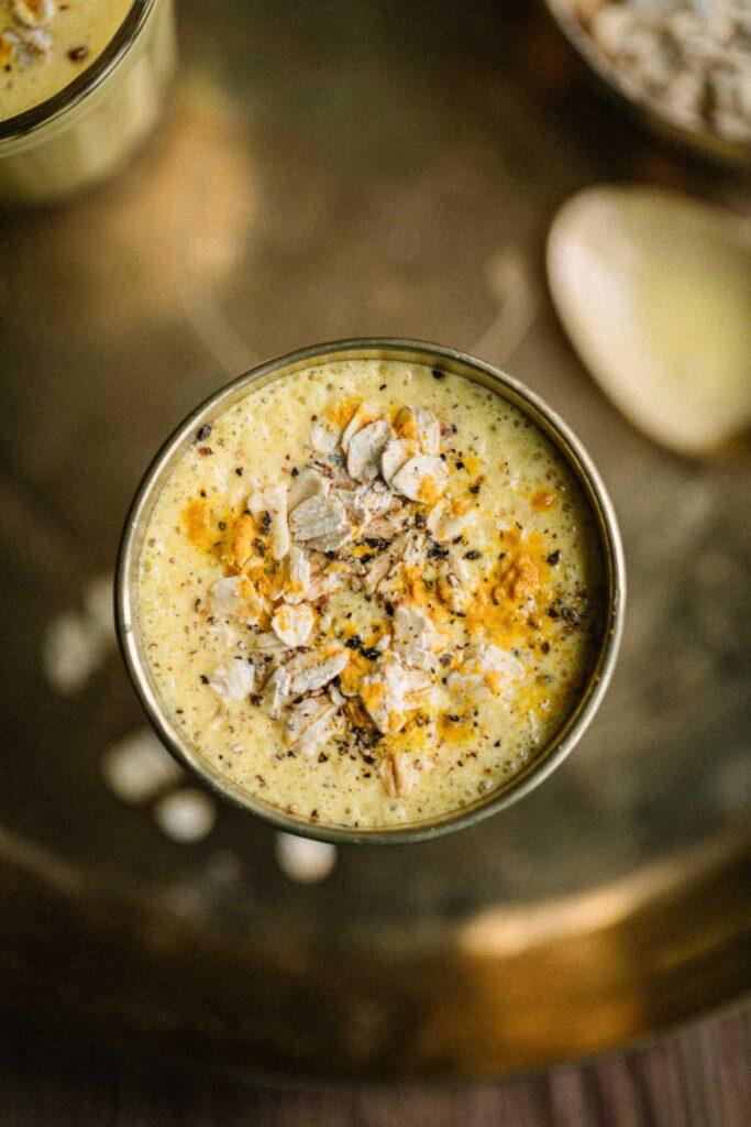 Closeup of Mango breakfast lassi with a sprinkling of oats, turmeric and cardamom.